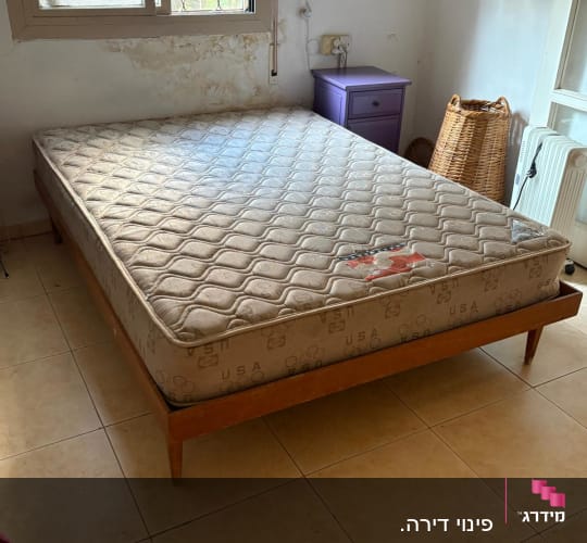 מיטה עם מזרן בחדר שינה עם קיר מתקלף